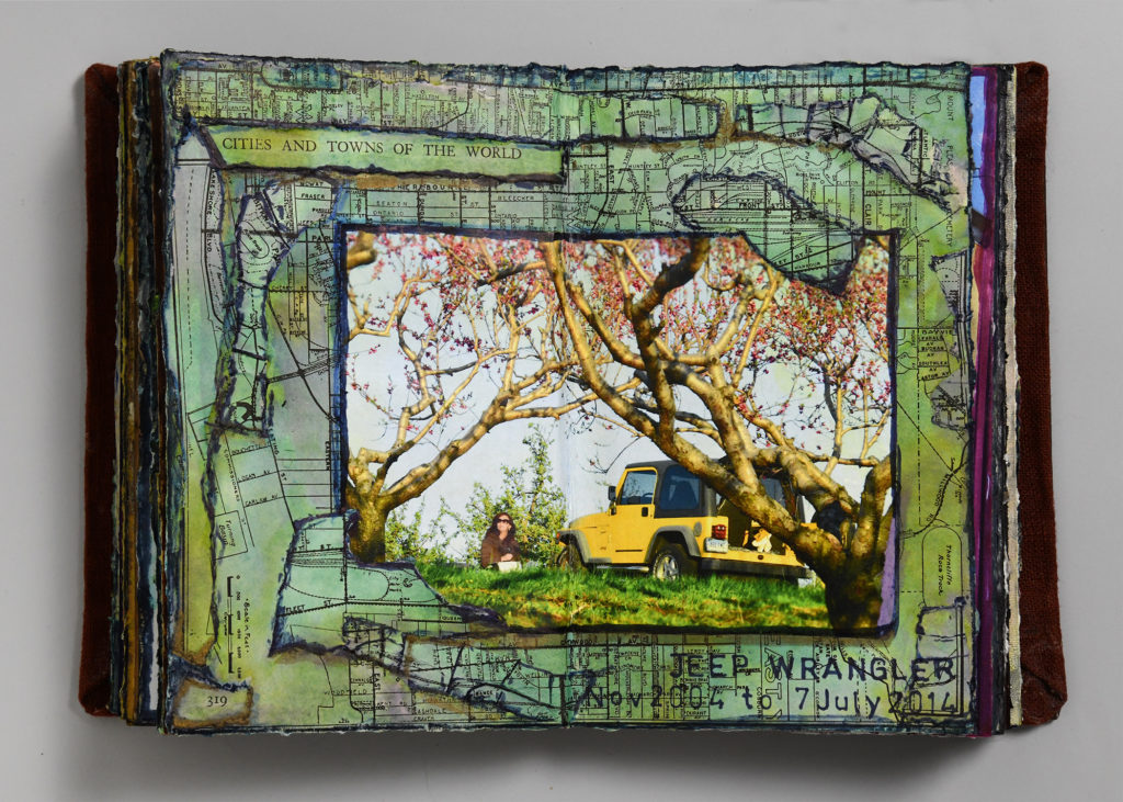 visual journal page with torn pieces of city maps surrounding a photo of a woman sitting in an orchard, next to a yellow Jeep Wrangler, working in a sketchbook