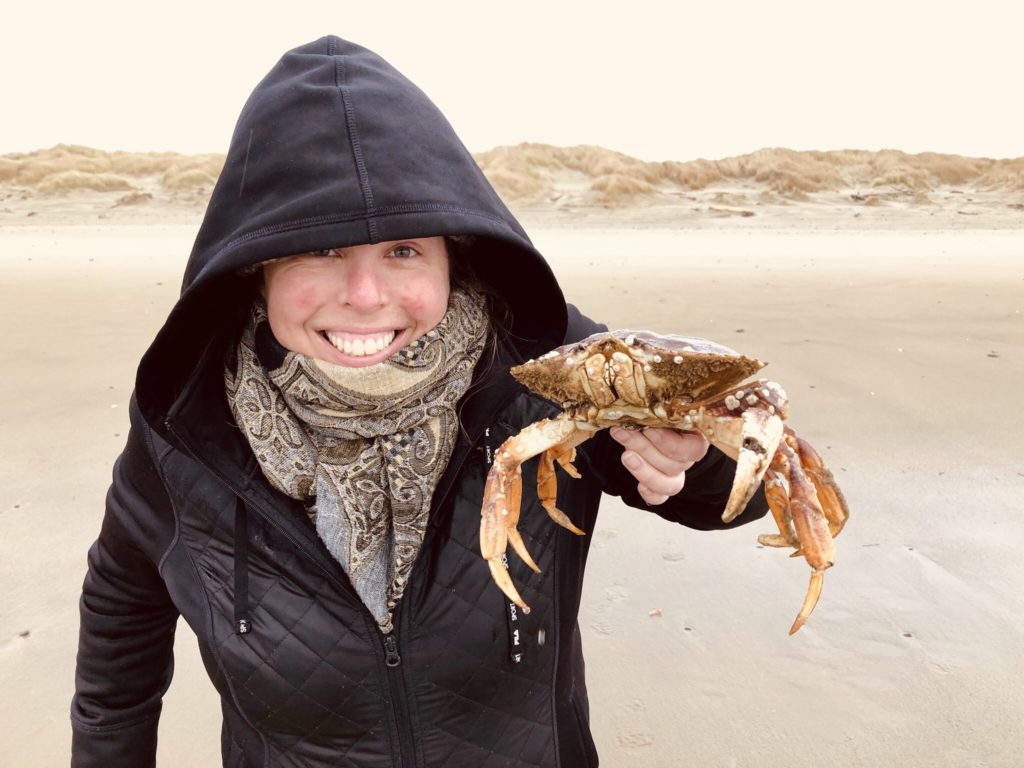 lady on a winter beach, holding a large rescued crab up for the camera